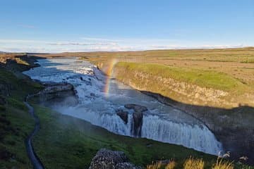 una imagen de las cascadas de Gullfoss con un arco iris desde un mirador superior durante la puesta de sol