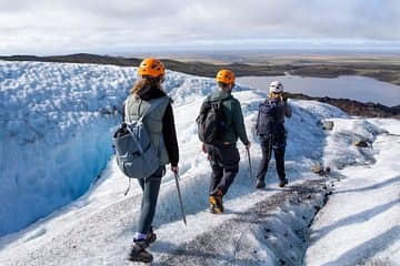 Hikers explore the icy terrain of a glacier in Vatnajokull National Park, carefully following each other in a line.