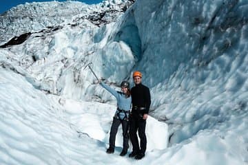 A couple hikes together across a frozen Skaftafell glacier in Iceland.
