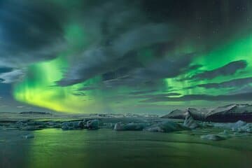Northern lights shine above Jokulsarlon Glacier Lagoon and its floating icebergs.