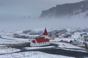 The village of Vik sits along the coast covered in snow during winter.