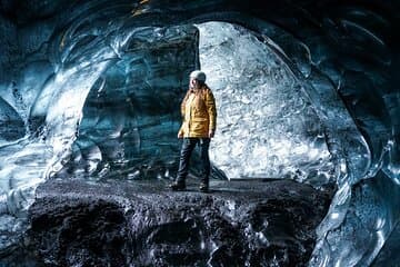 A woman walks through an ice cave and pauses to admire the frozen shapes.
